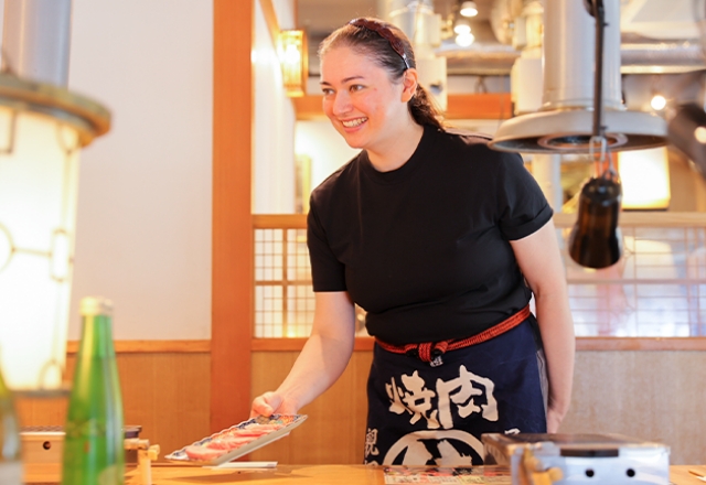 笑顔で料理を提供する外国人スタッフのAさん